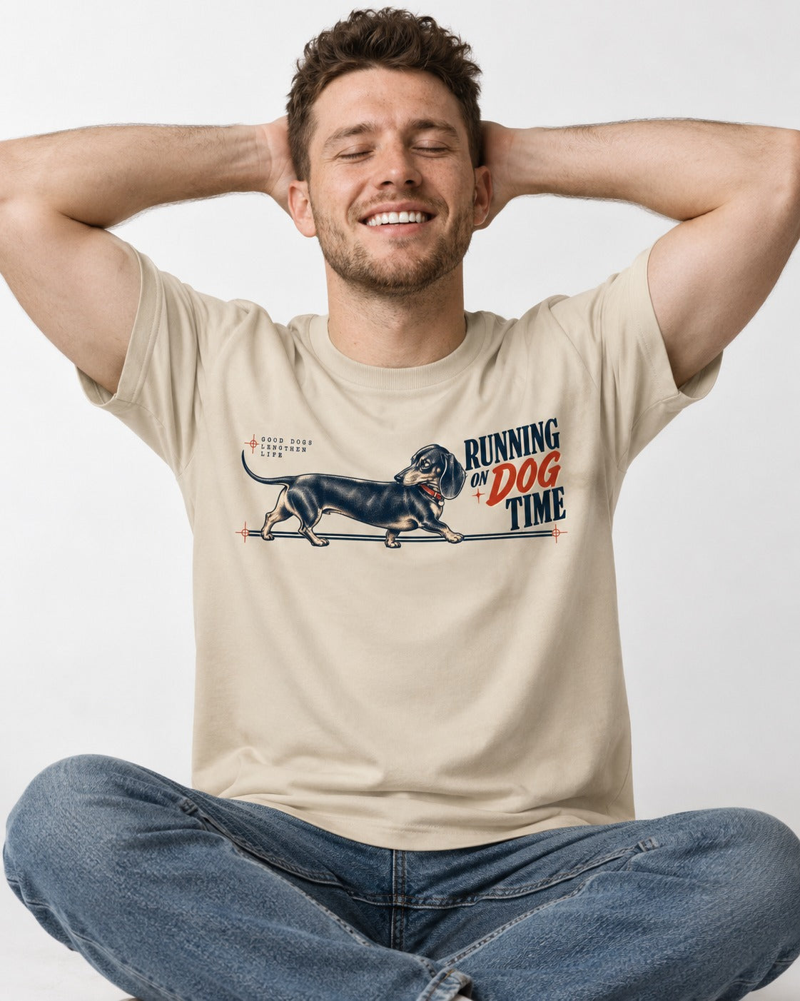 Dachshund Lengthens Life T-Shirt in Sand, worn by a seated model