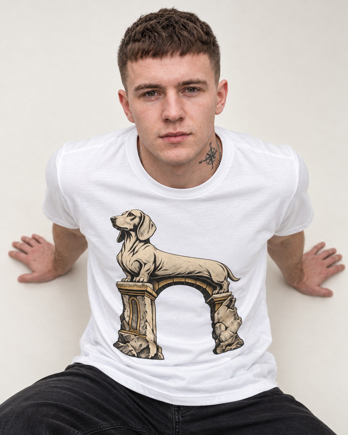 Dachshund Ruined Stone Arch Monument Graphic T-Shirt in White, worn by a seated model