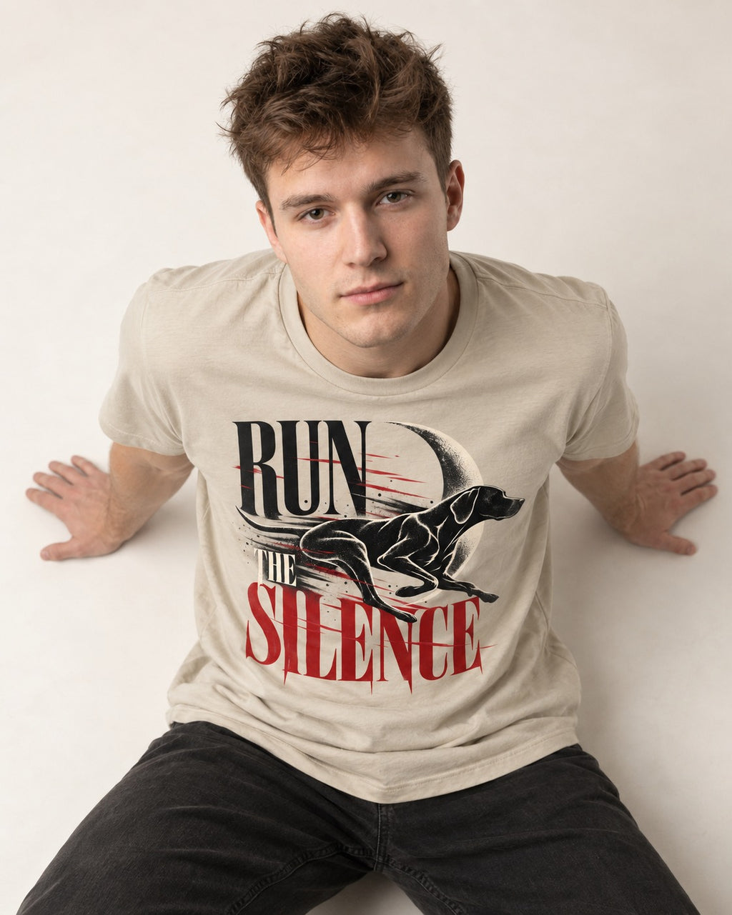 Run the Silence German Shorthaired Pointer T-Shirt in Sand, worn by a seated model
