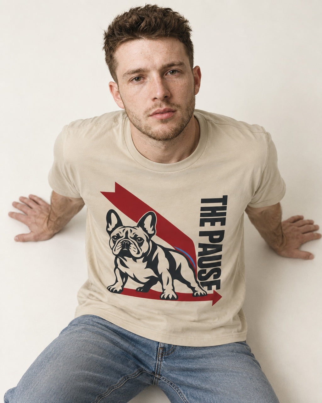 The Frenchie Pause T-Shirt in Sand, worn by a seated model