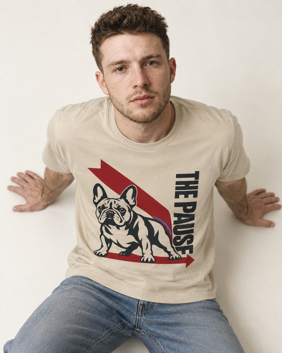 The Frenchie Pause T-Shirt in Sand, worn by a seated model