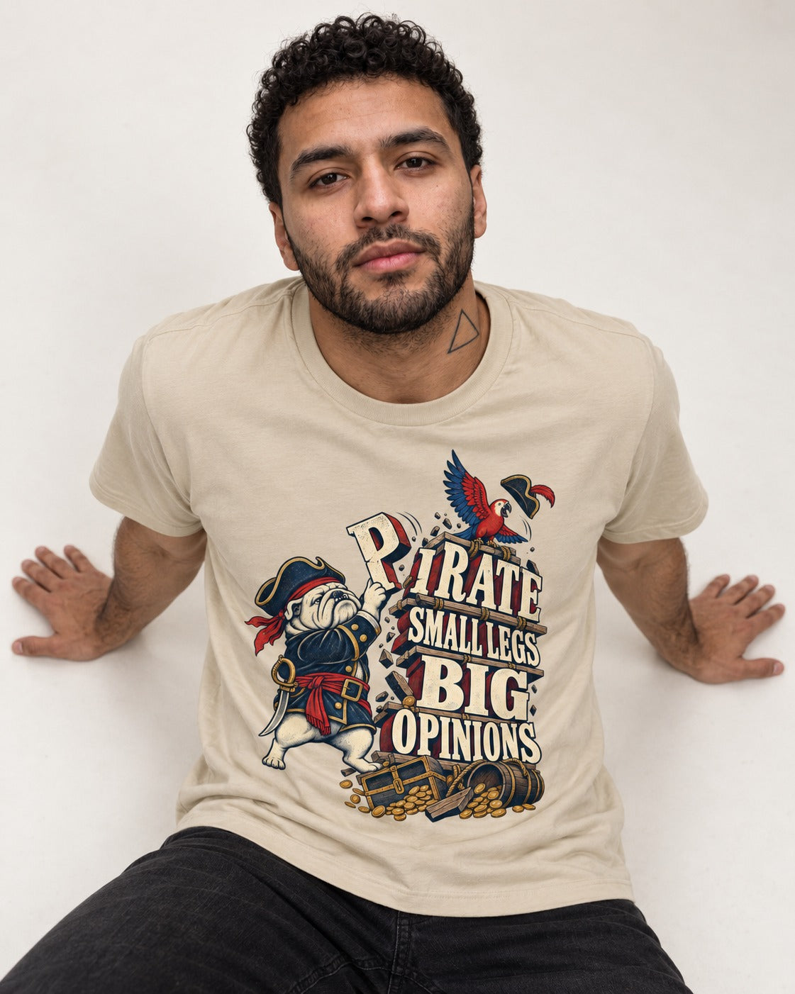 Pirate English Bulldog Big Opinions T-Shirt in Sand, worn by a seated model