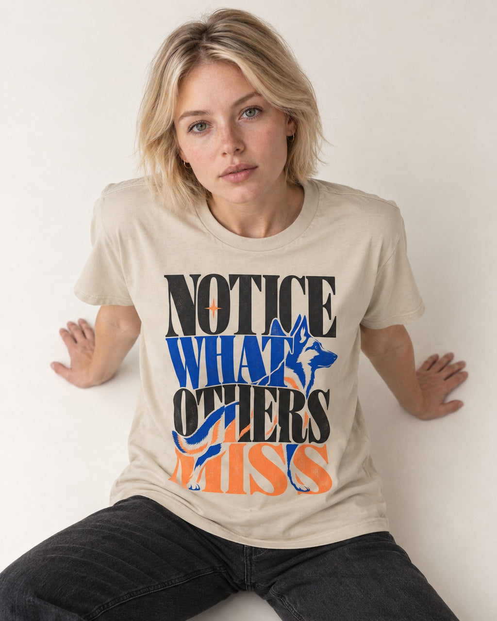 Notice What Others Miss German Shepherd Dog T-Shirt in Sand, worn by a seated model