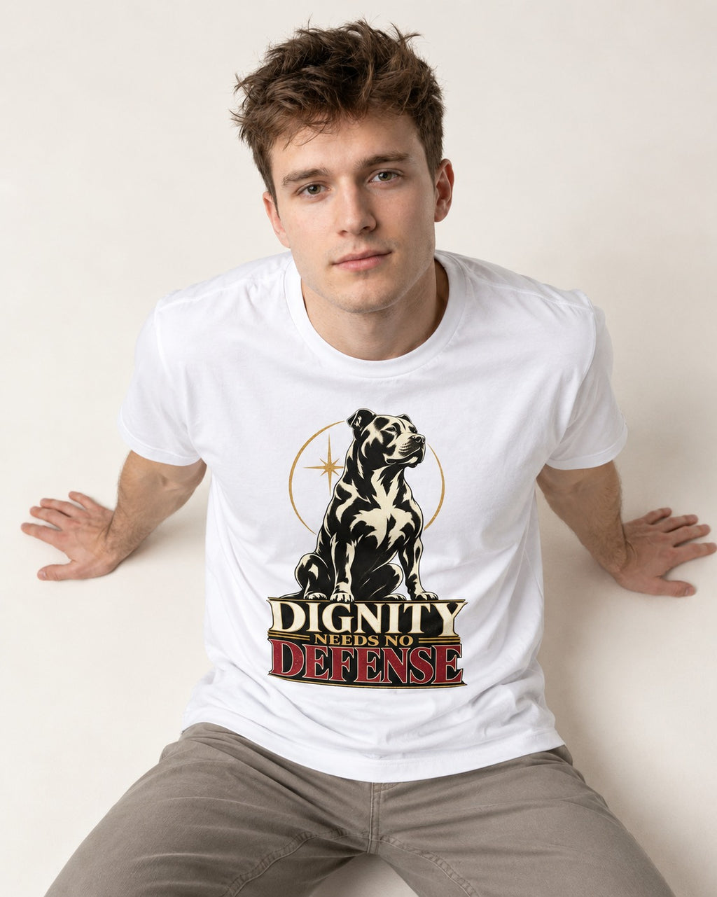 Pitbull Dignity Needs No Defense Seated Emblem Graphic T-Shirt in White, worn by a seated model