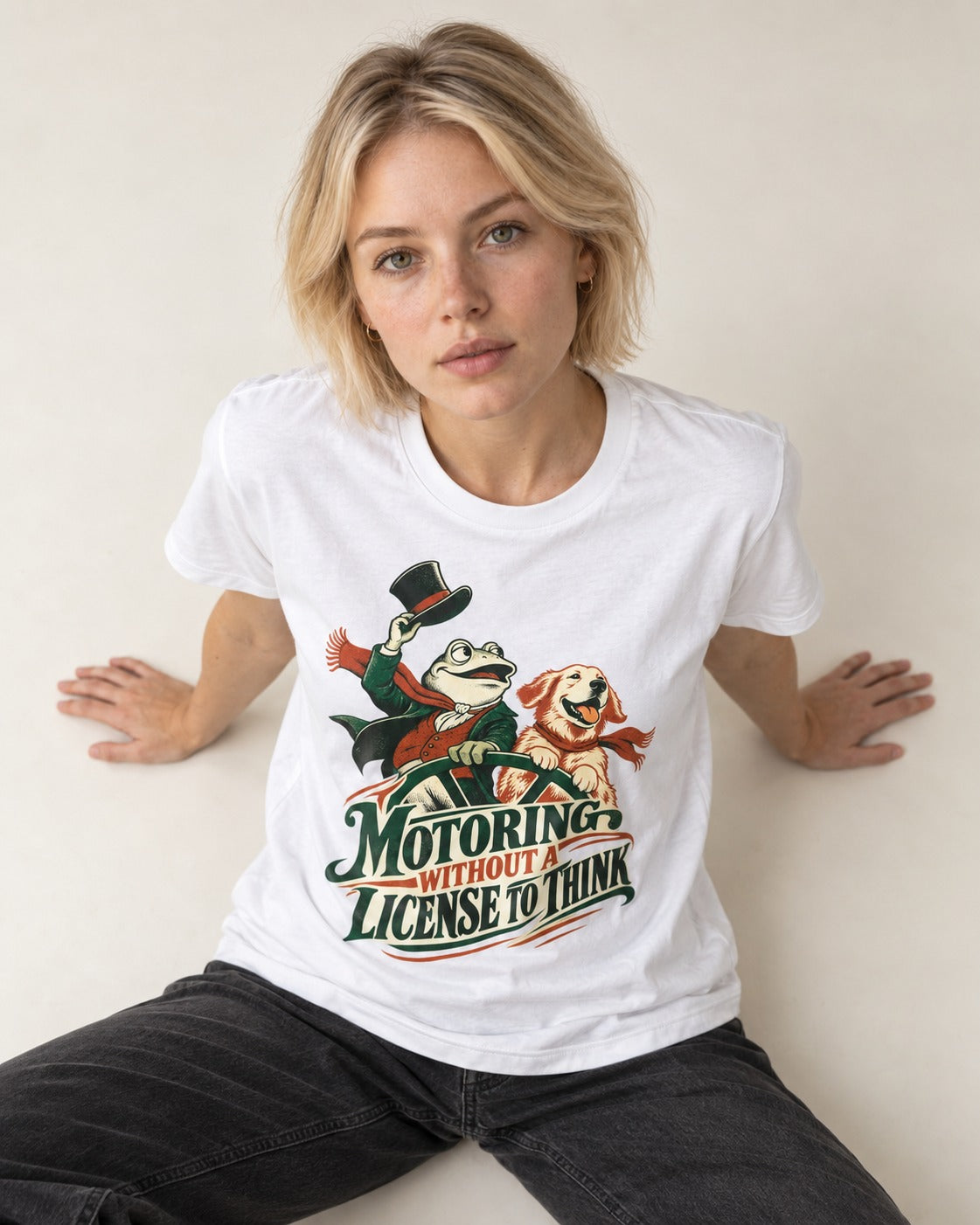 Golden Retriever Motoring Without a License to Think Driving Graphic T-Shirt in White, worn by a seated model