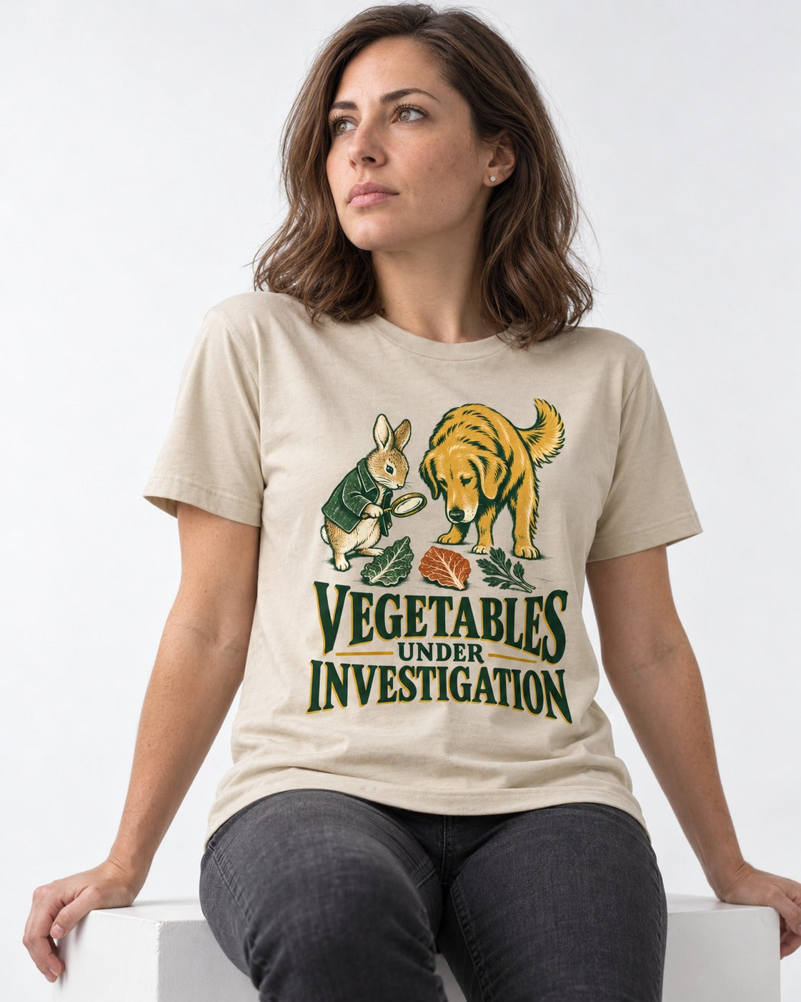 Golden Retriever Vegetables Under Investigation Rabbit Detective Graphic T-Shirt in Sand, worn by a seated model