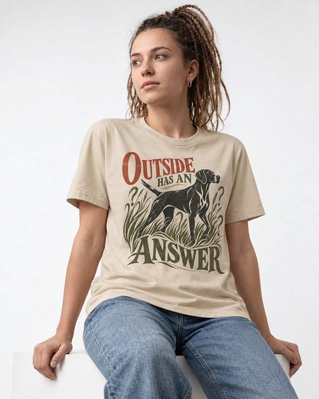 Outside Has an Answer German Shorthaired Pointer T-Shirt in Sand, worn by a seated model