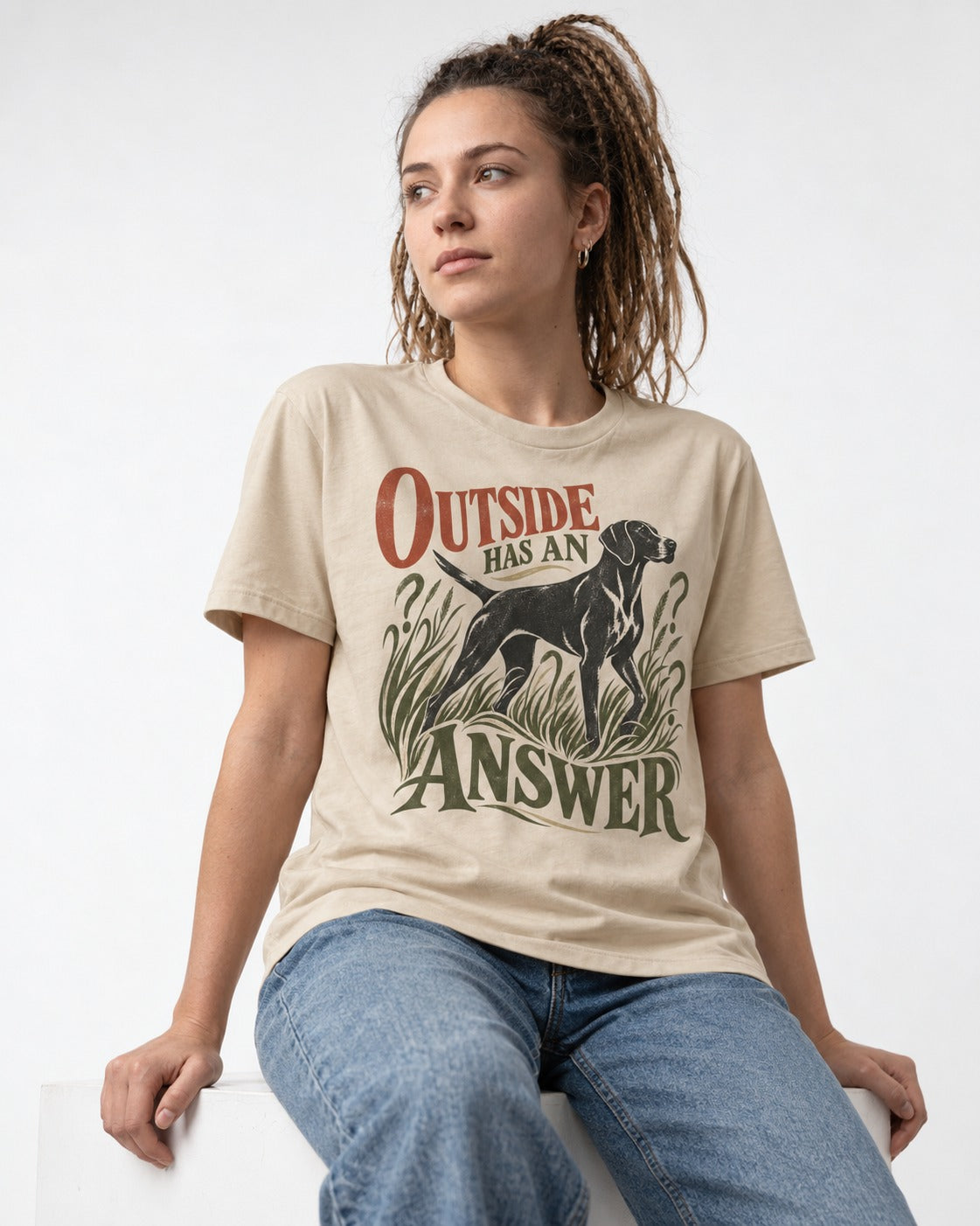 Outside Has an Answer German Shorthaired Pointer T-Shirt in Sand, worn by a seated model