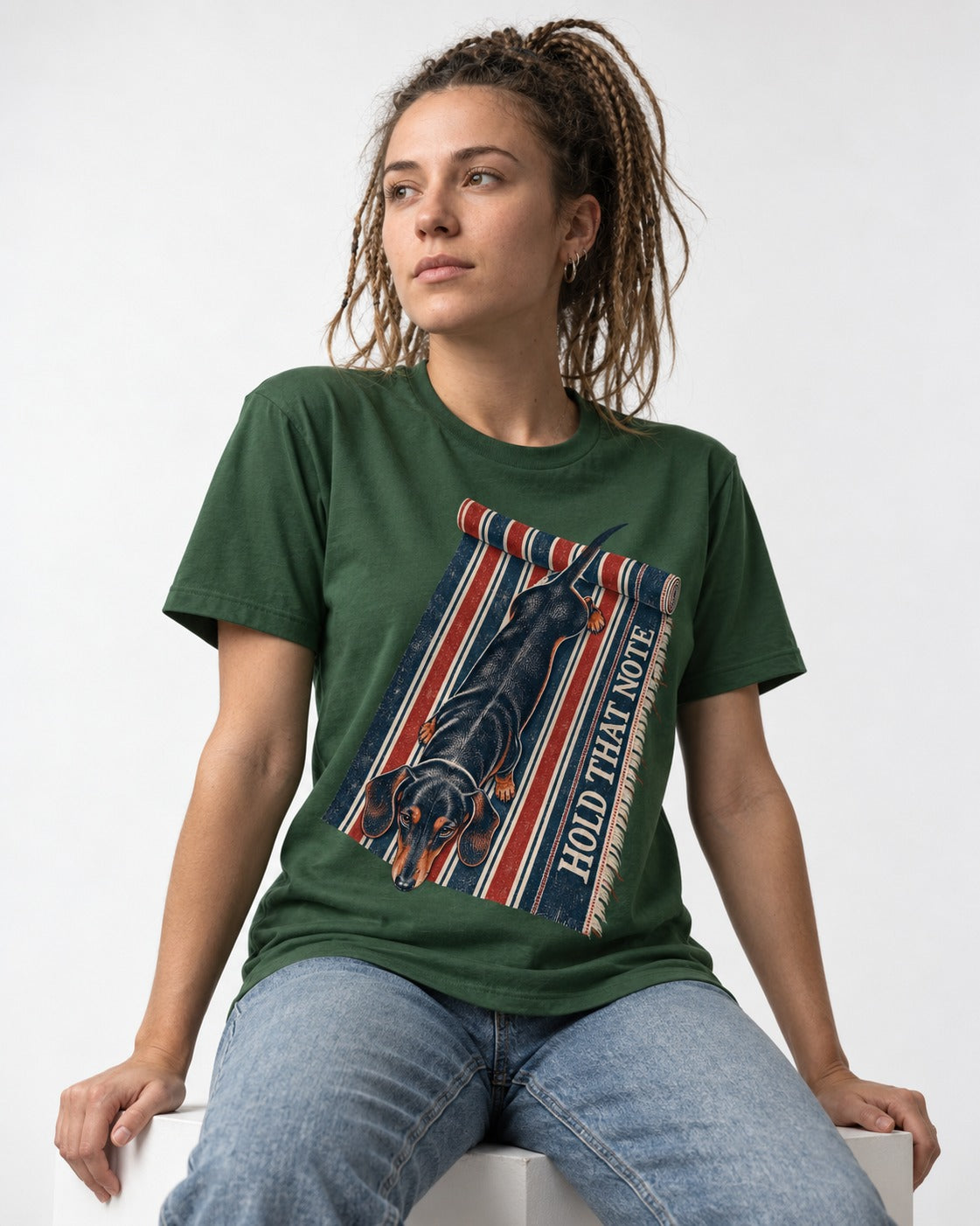 Dachshund Hold That Note Striped Rug Graphic T-Shirt in Forest Green, worn by a seated model