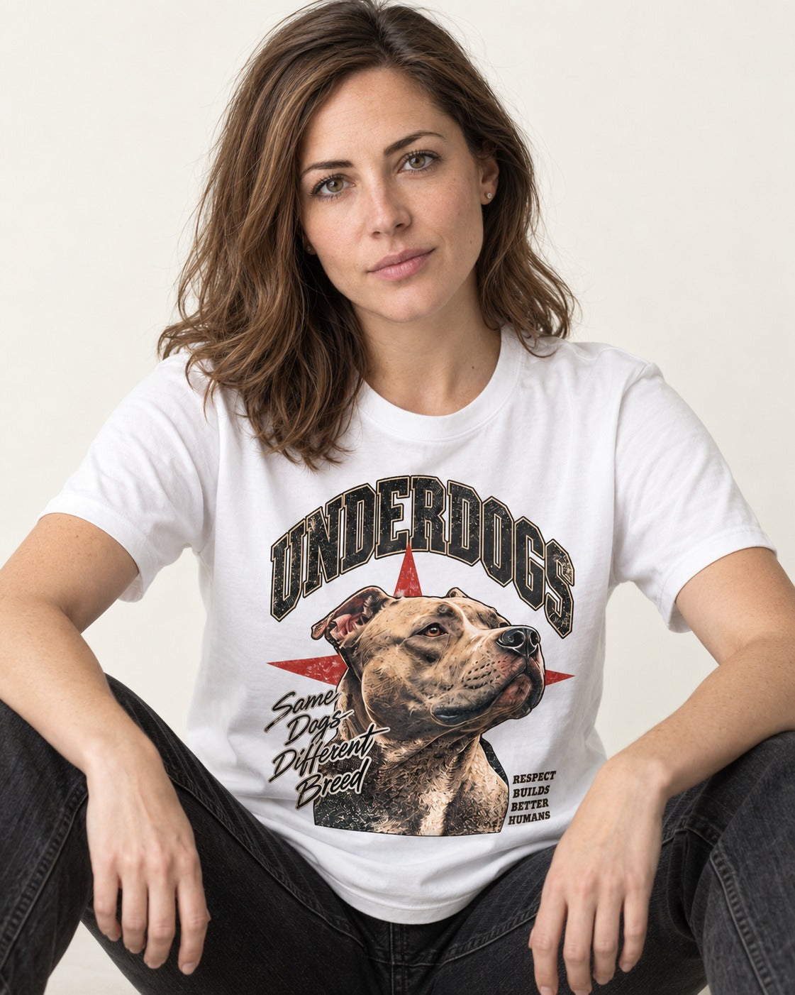 Pitbull Underdogs Same Dogs Different Breed Portrait Graphic T-Shirt in White, worn by a seated model