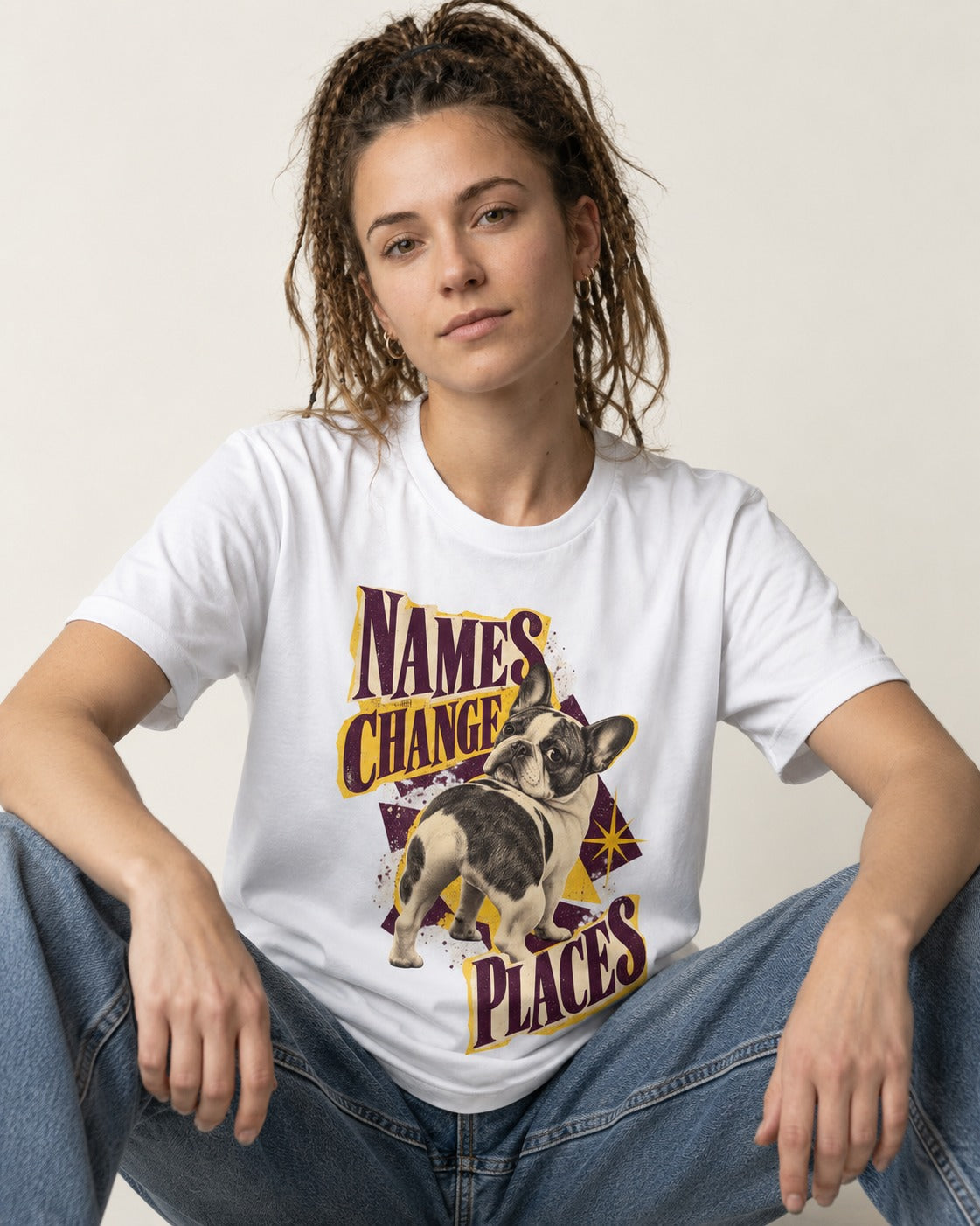 Frenchie Names Change Places Purple Poster Graphic T-Shirt in White, worn by a seated model