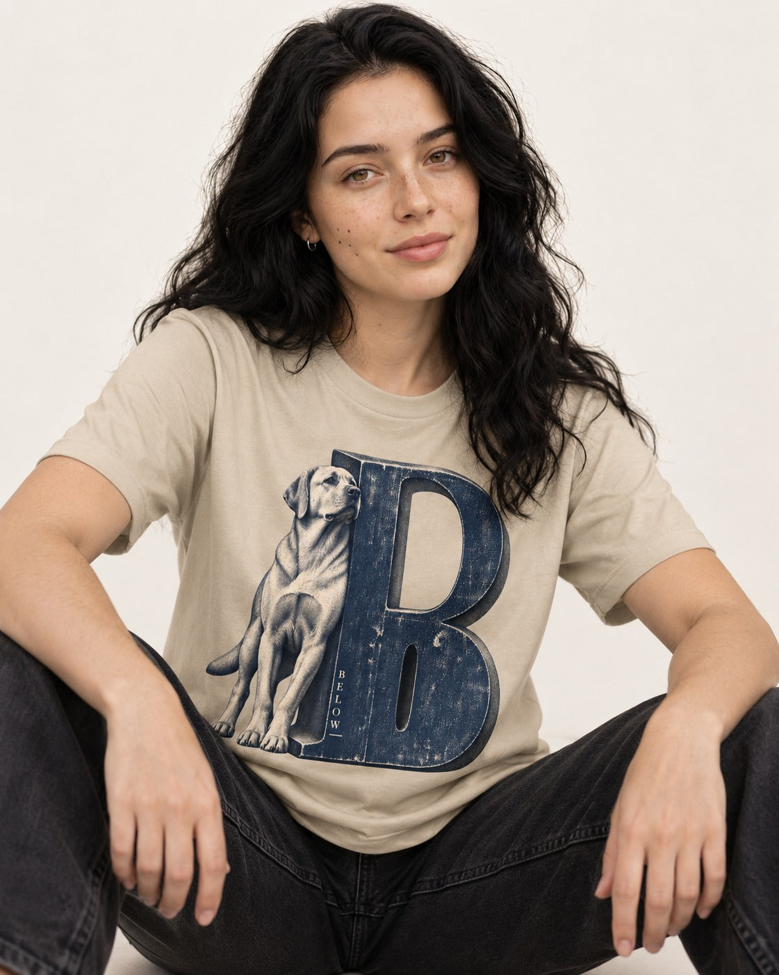 Labrador Retriever Below T-Shirt in Sand, worn by a seated model
