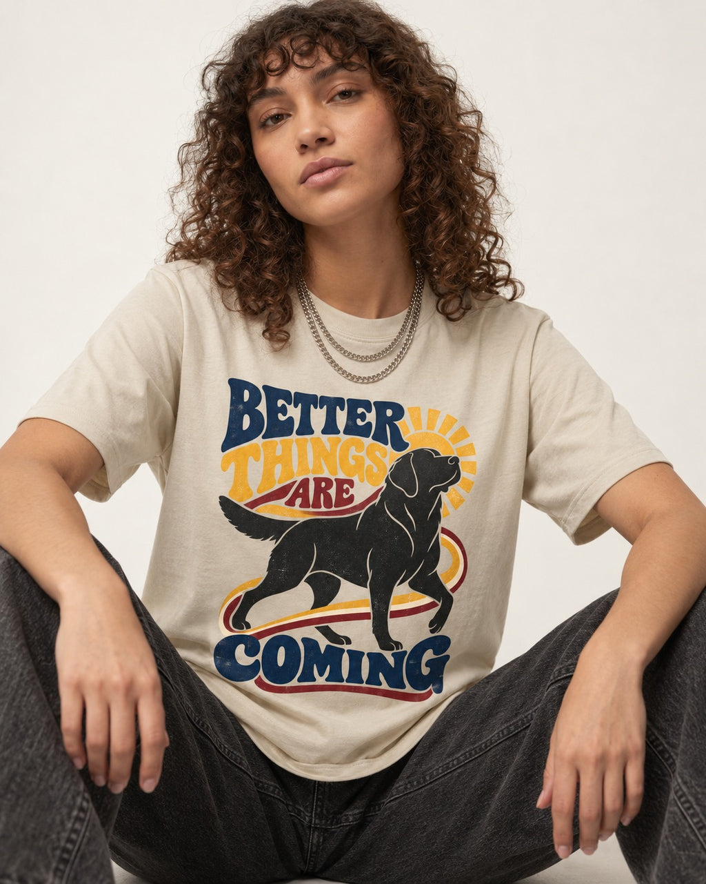 Better Things Are Coming Labrador Retriever T-Shirt in Sand, worn by a seated model