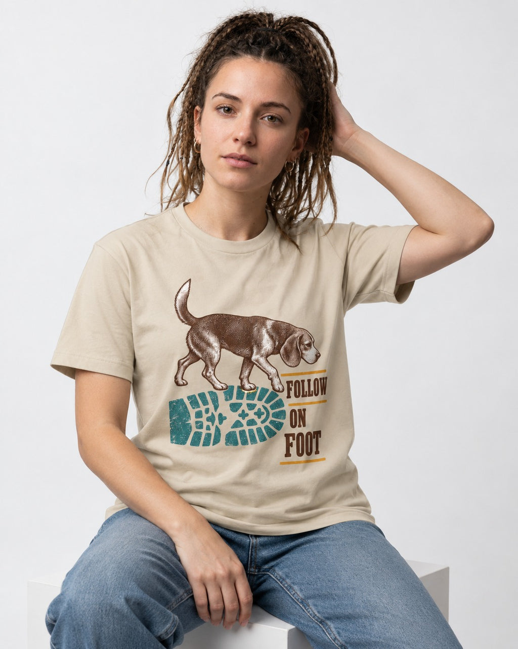 Follow the Beagle on Foot T-Shirt in Sand, worn by a seated model