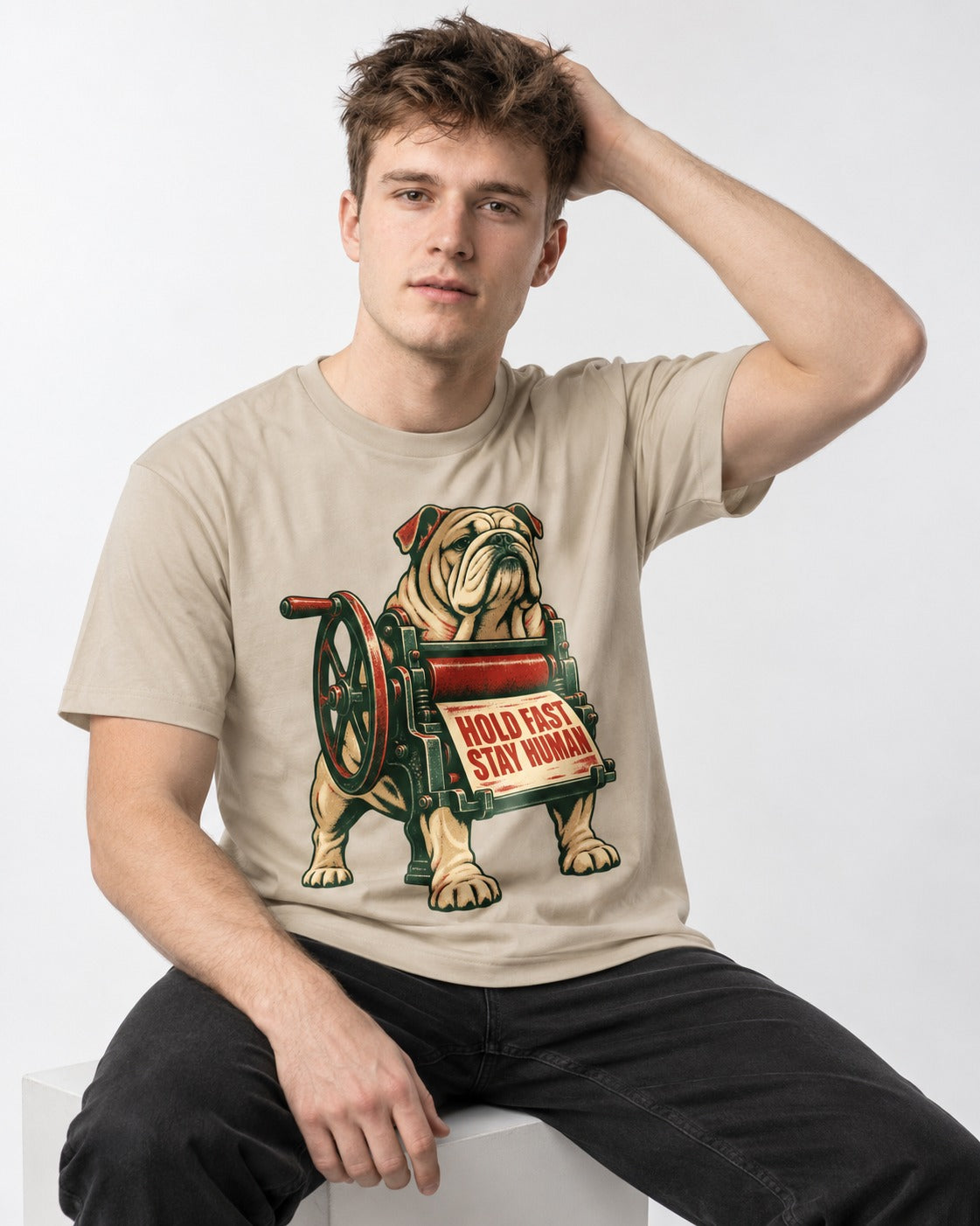 Hold Fast Stay Human English Bulldog T-Shirt in Sand, worn by a seated model