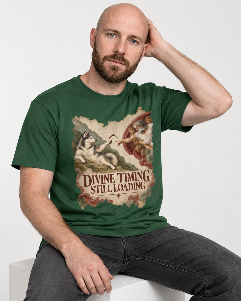 Husky Divine Timing Still Loading Creation Parody Graphic T-Shirt in Forest Green, worn by a seated model