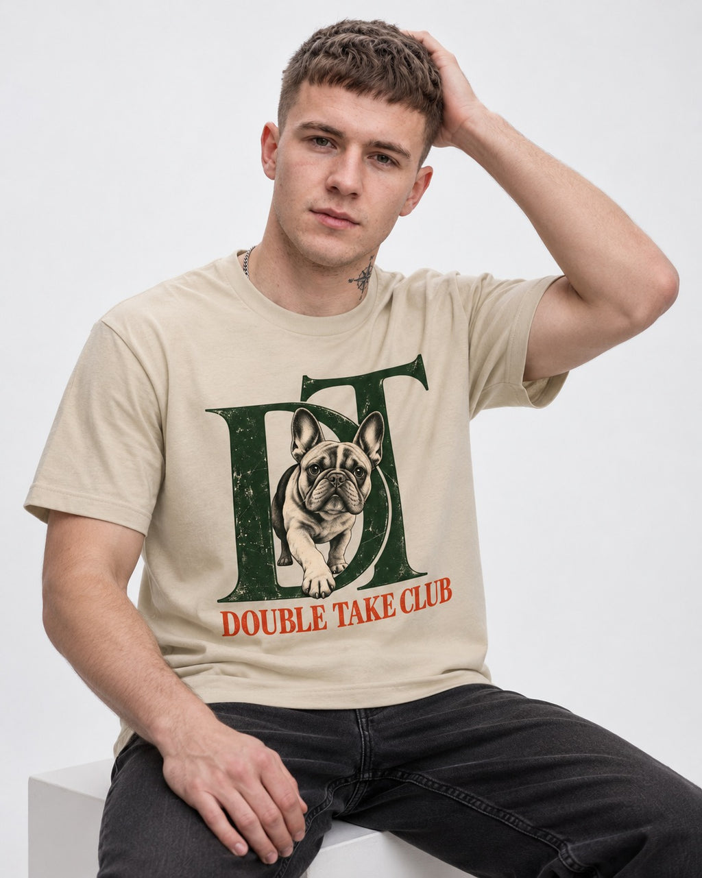Frenchie Double Take Club T-Shirt in Sand, worn by a seated model