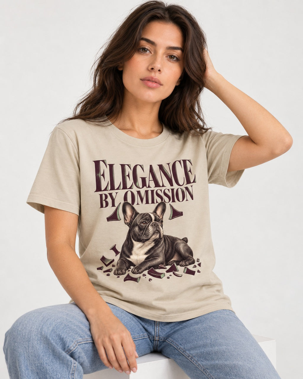 Frenchie Elegance by Omission T-Shirt in Sand, worn by a seated model