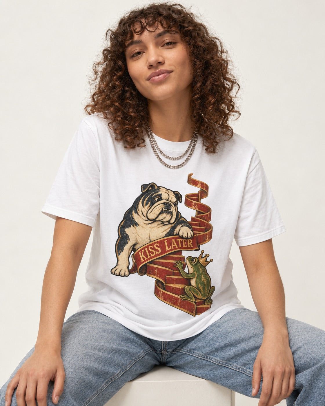English Bulldog Kiss Later Frog Prince Graphic T-Shirt in White, worn by a seated model