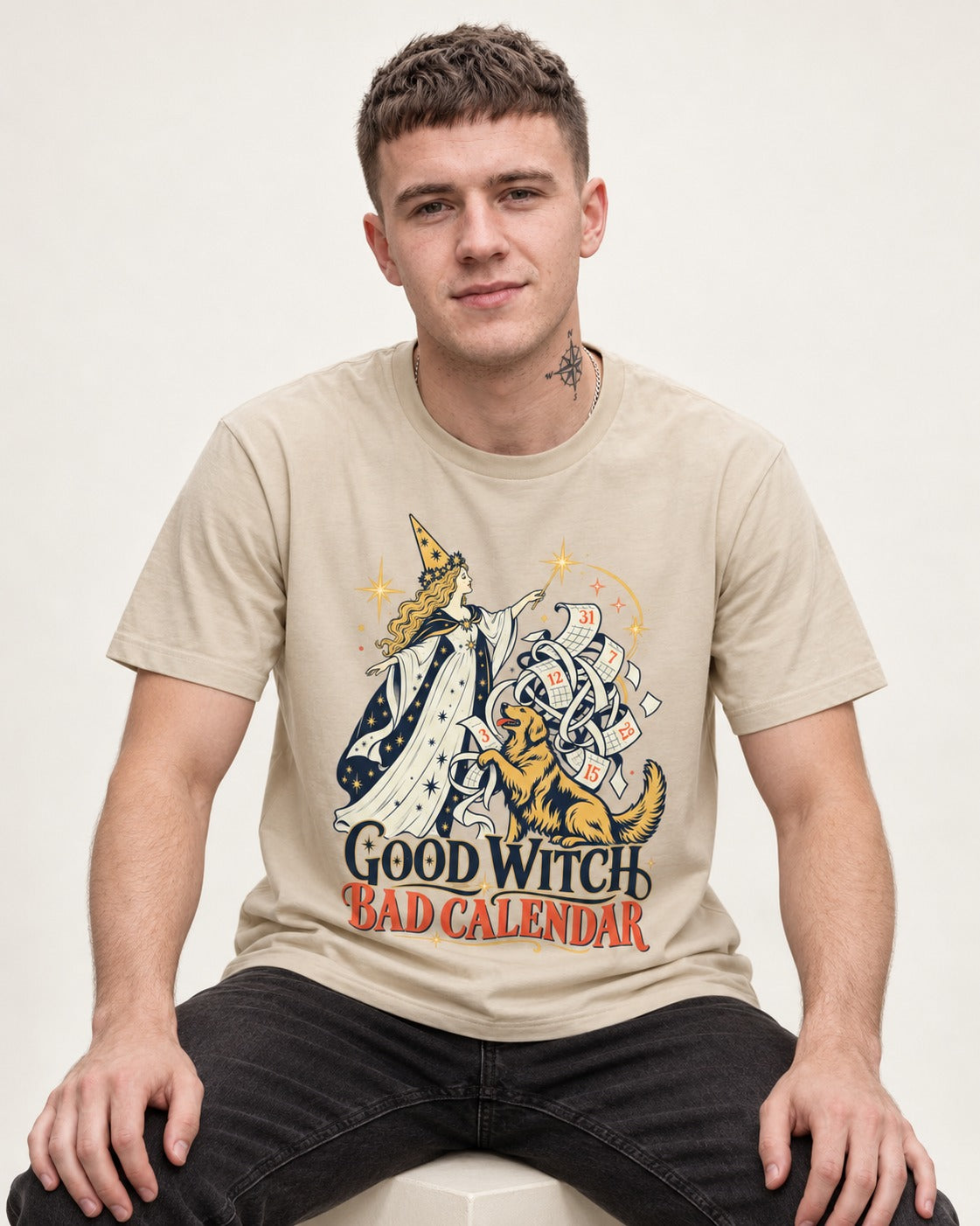 Good Witch Bad Calendar Golden Retriever T-Shirt in Sand, worn by a seated model