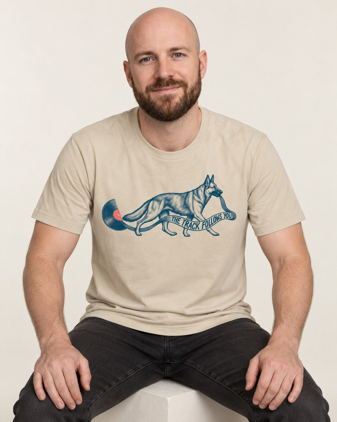 German Shepherd Dog The Track Follows You T-Shirt in Sand, worn by a seated model