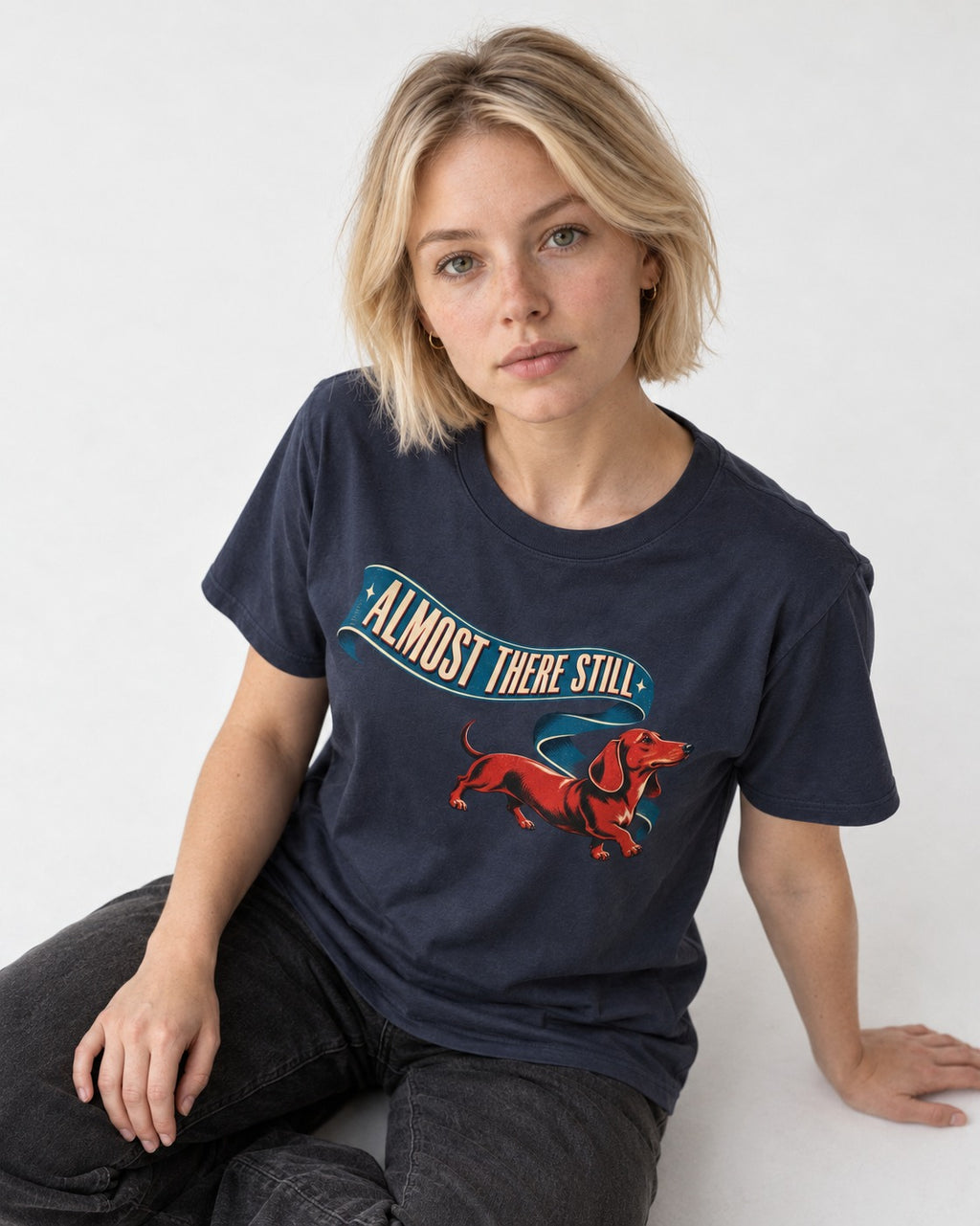 Dachshund Almost There Still Ribbon Graphic T-Shirt in Navy, worn by a seated model