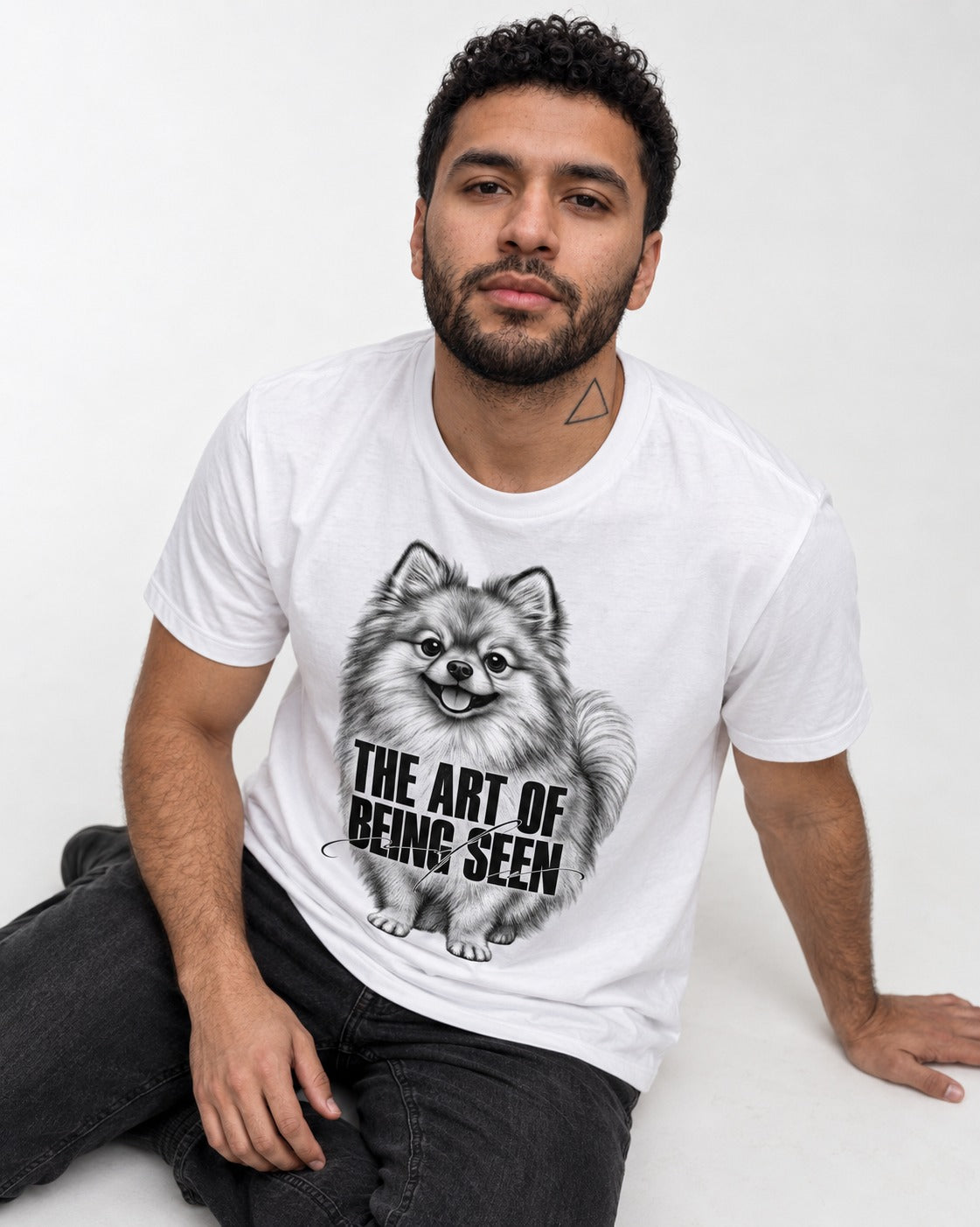 Pomeranian The Art of Being Seen Portrait Graphic T-Shirt in White, worn by a seated model