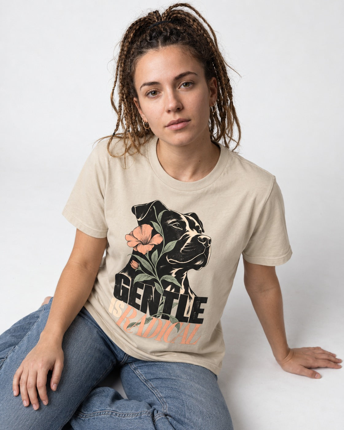 Gentle Pitbull Is Radical T-Shirt in Sand, worn by a seated model