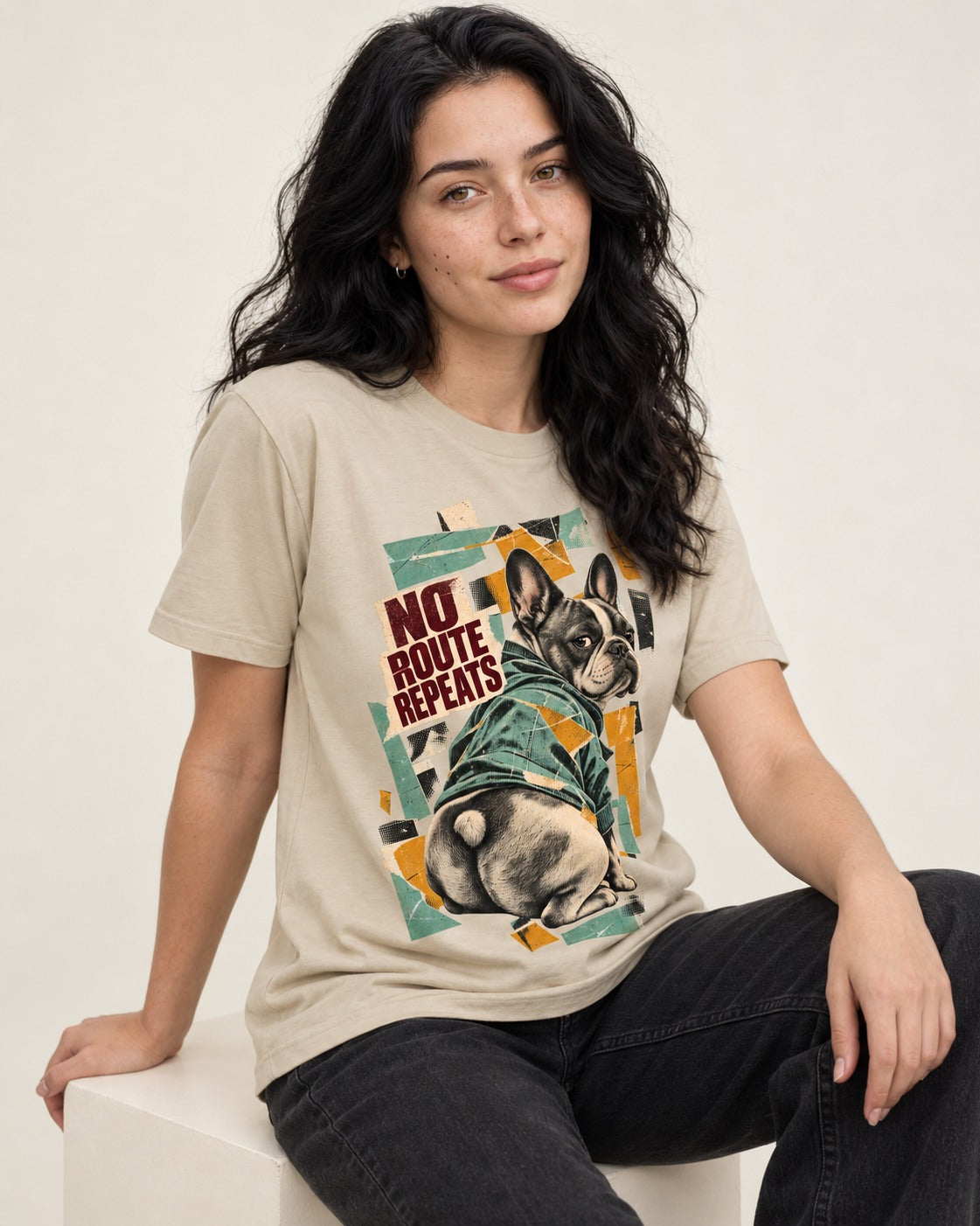 No Route Repeats Frenchie T-Shirt in Sand, worn by a seated model