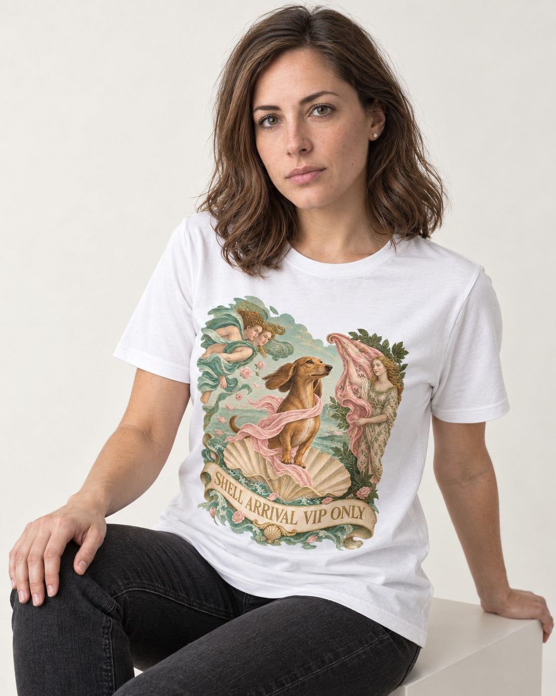 Dachshund Shell Arrival VIP Only Venus Parody Graphic T-Shirt in White, worn by a seated model