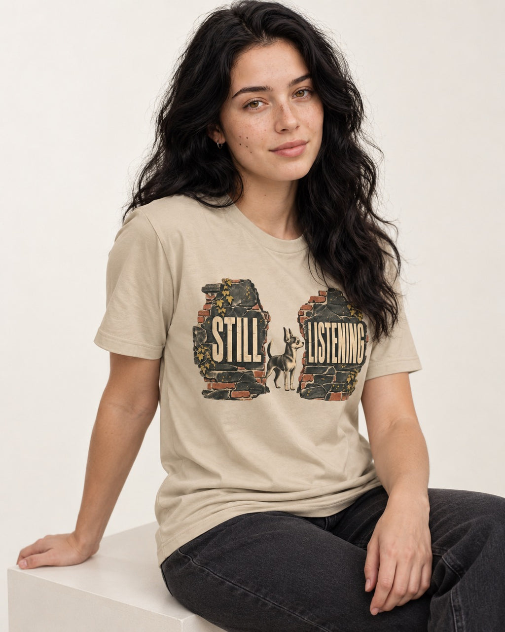 Chihuahua Still Listening T-Shirt in Sand, worn by a seated model