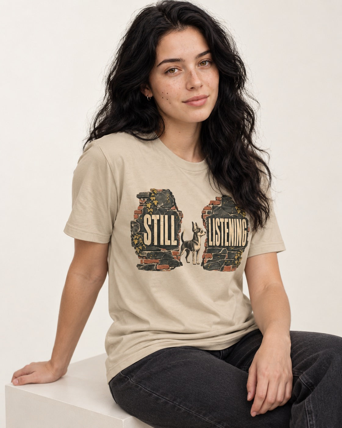 Chihuahua Still Listening T-Shirt in Sand, worn by a seated model