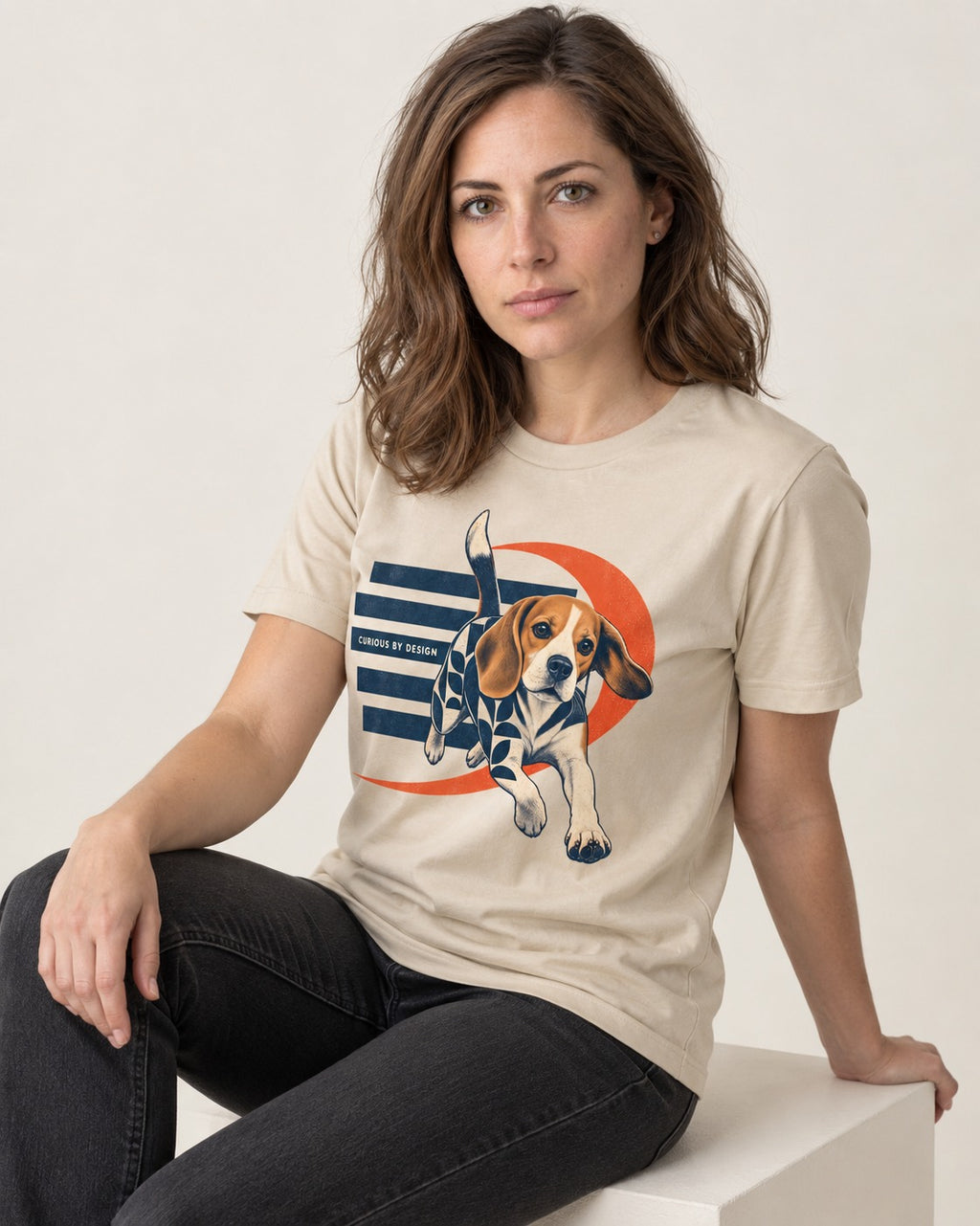Beagle Born Curious T-Shirt in Sand, worn by a seated model