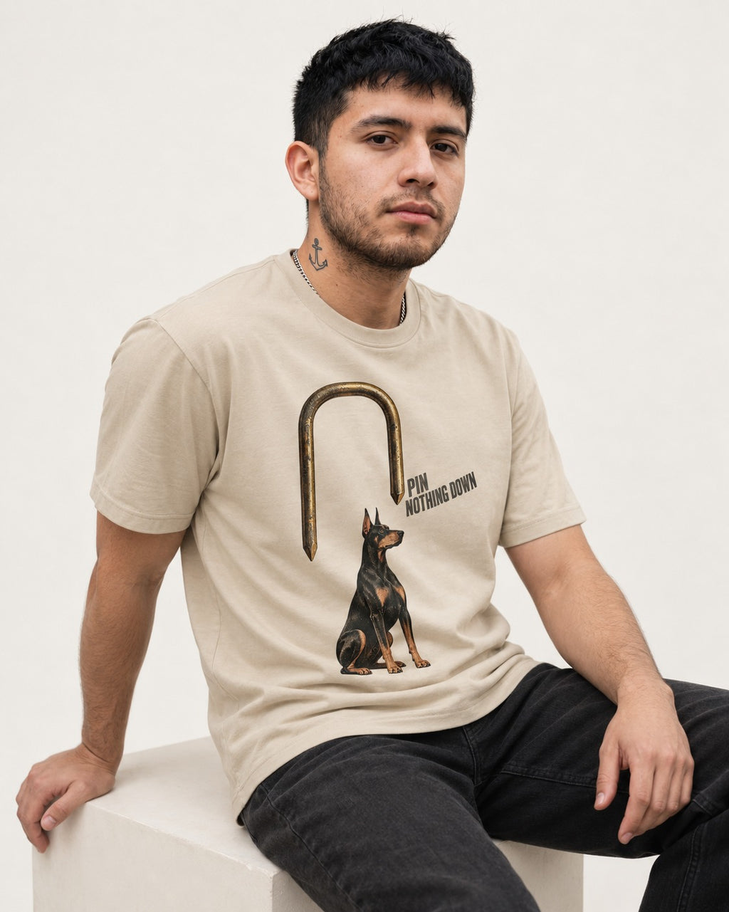 Nothing Pins Doberman Down T-Shirt in Sand, worn by a seated model
