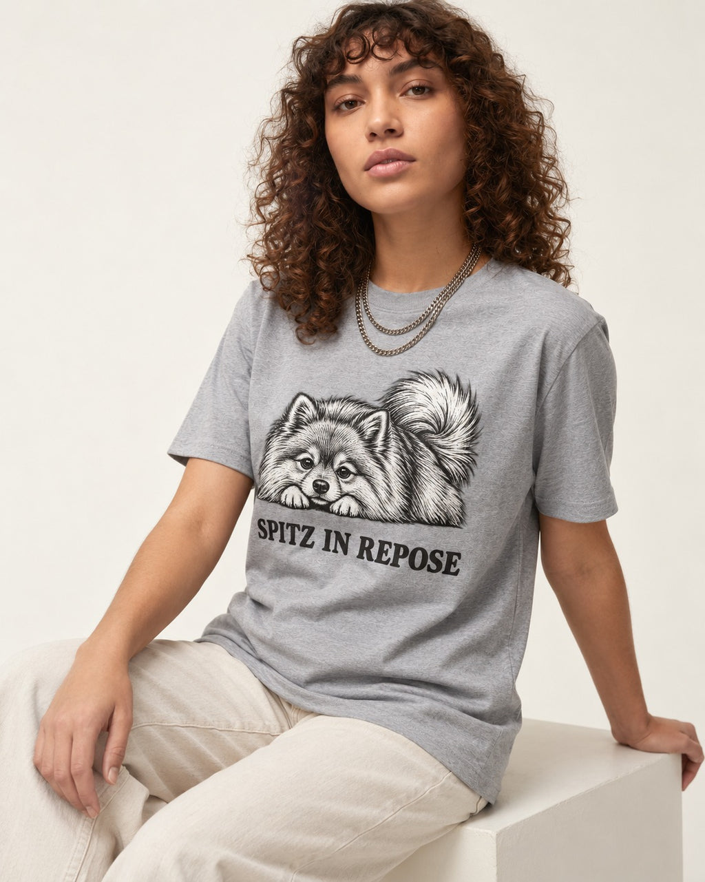 Pomeranian In Repose T-Shirt in Sport Grey, worn by a seated model