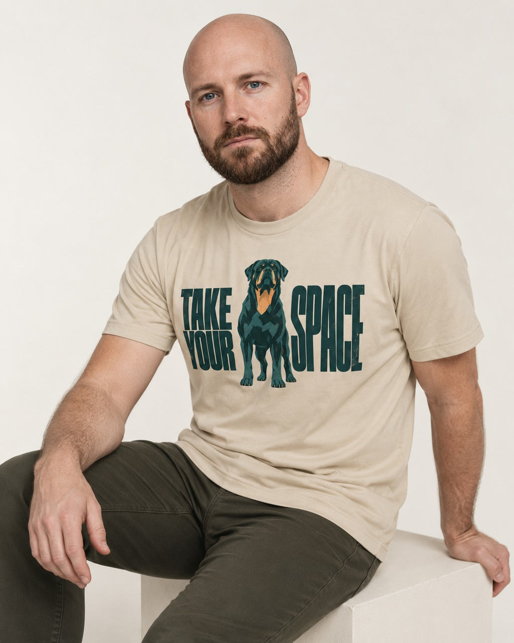 Rottweiler Take Your Space T-Shirt in Sand, worn by a seated model
