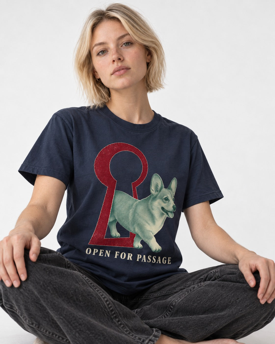 Corgi Open for Passage Keyhole Graphic T-Shirt in Navy, worn by a seated model