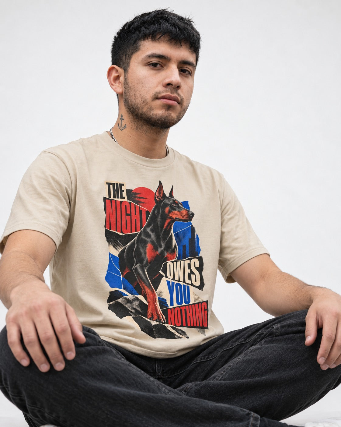 Night Owes You Nothing Doberman T-Shirt in Sand, worn by a seated model