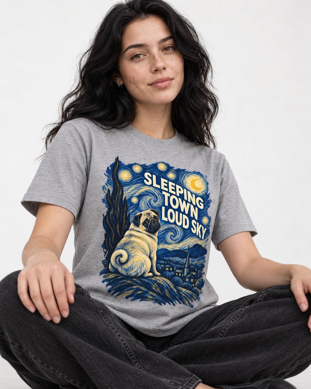 Pug Sleeping Town Loud Sky Starry Night Graphic T-Shirt in Sport Grey, worn by a seated model