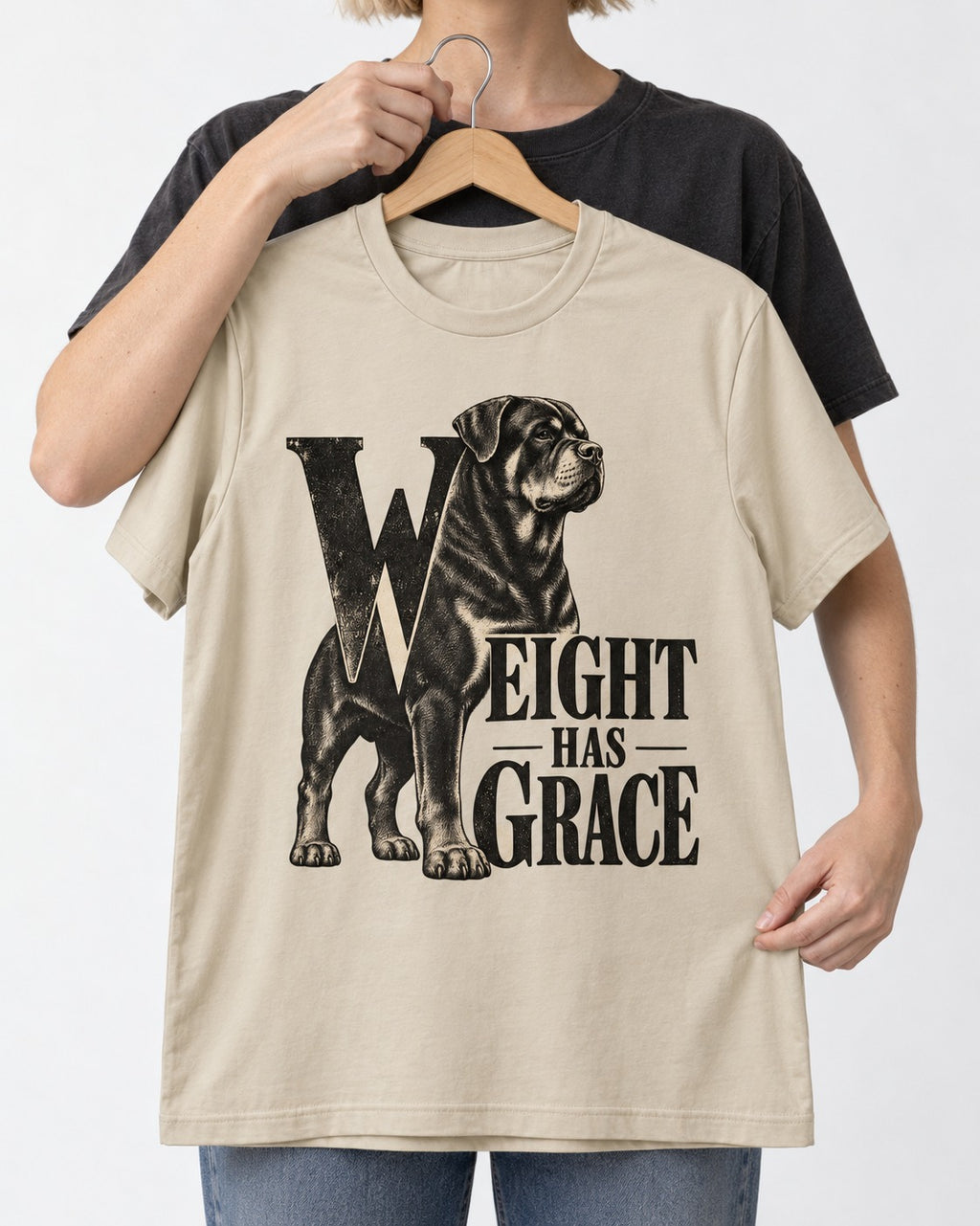 Rottweiler Weight Has Grace T-Shirt in Sand, held up on a hanger