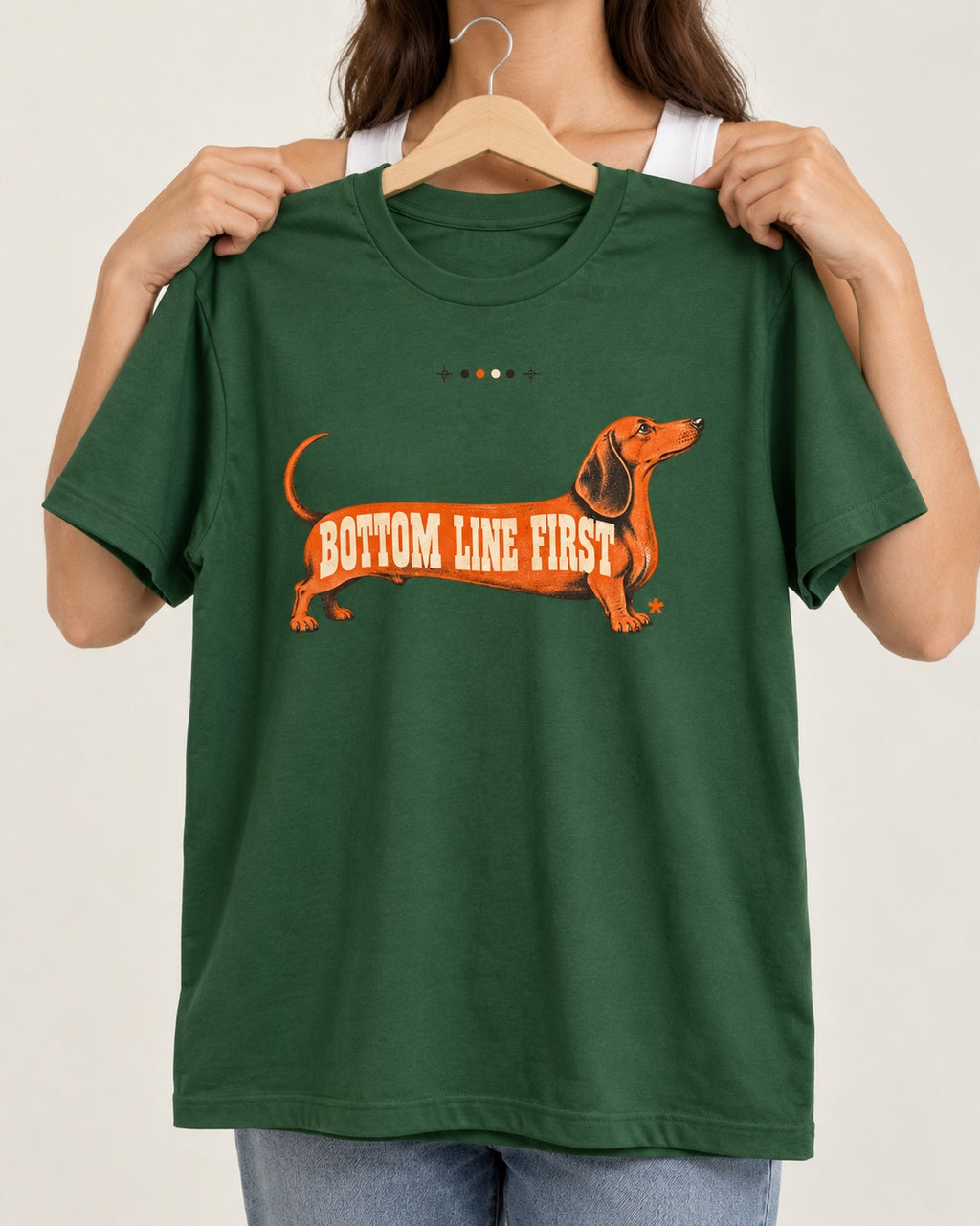 Dachshund Bottom Line First Body Lettering Graphic T-Shirt in Forest Green, held up on a hanger