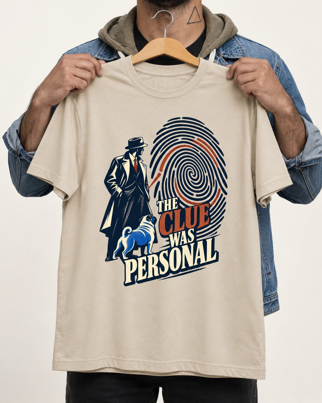 The Pug Clue Was Personal T-Shirt in Sand, held up on a hanger