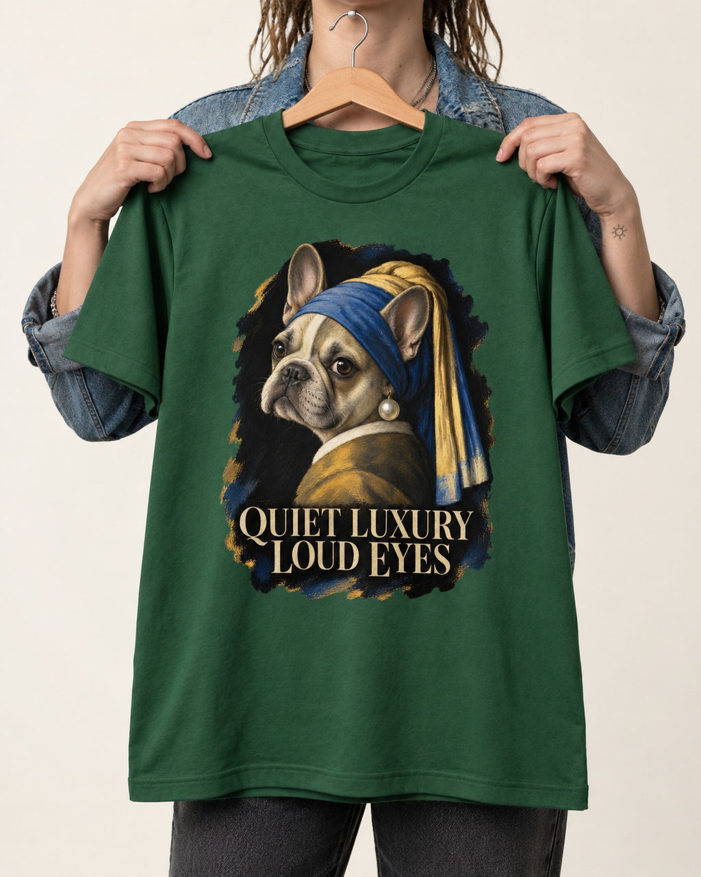 Frenchie Quiet Luxury Loud Eyes Pearl Portrait Graphic T-Shirt in Forest Green, held up on a hanger