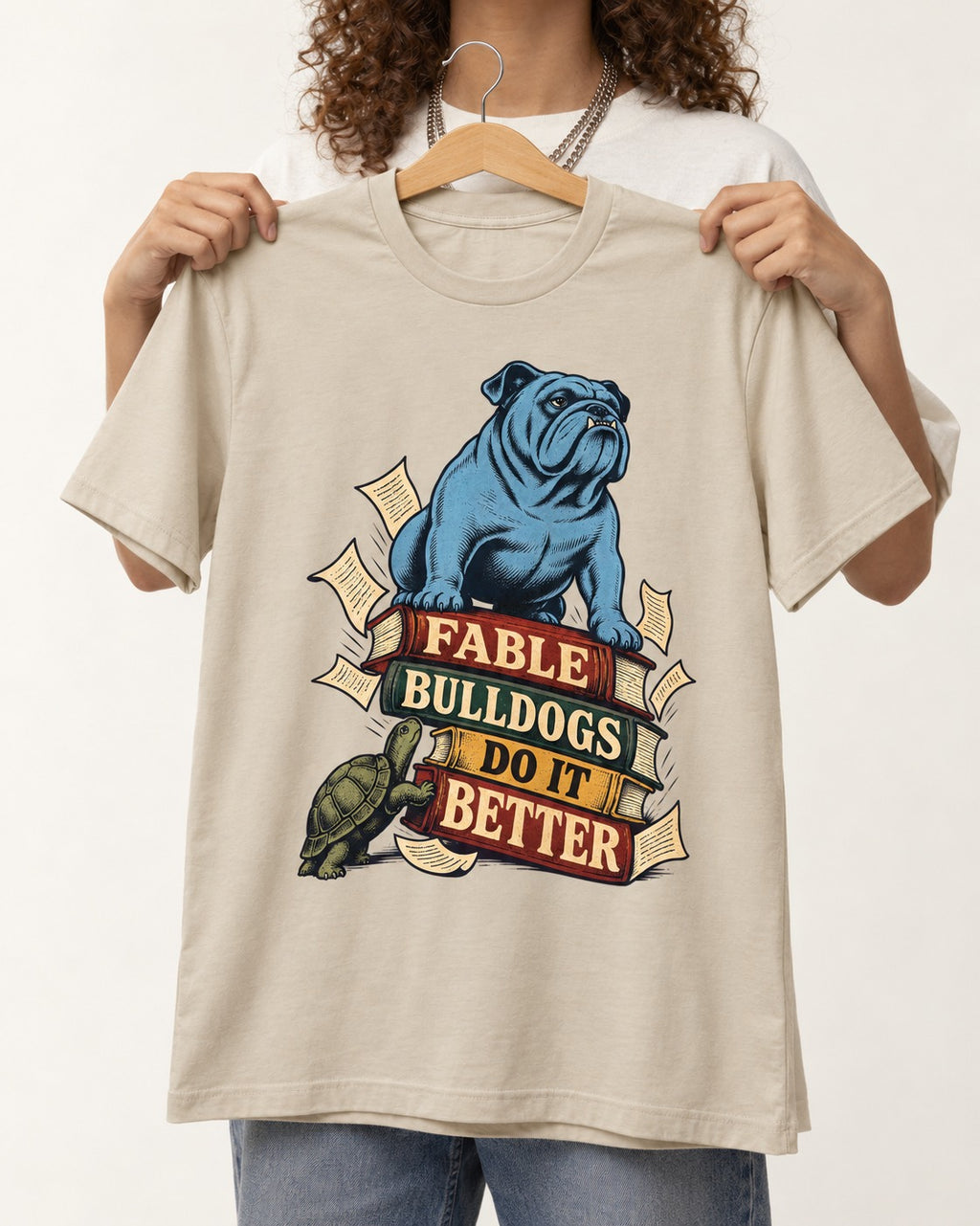 English Bulldog Does It Better T-Shirt in Sand, held up on a hanger