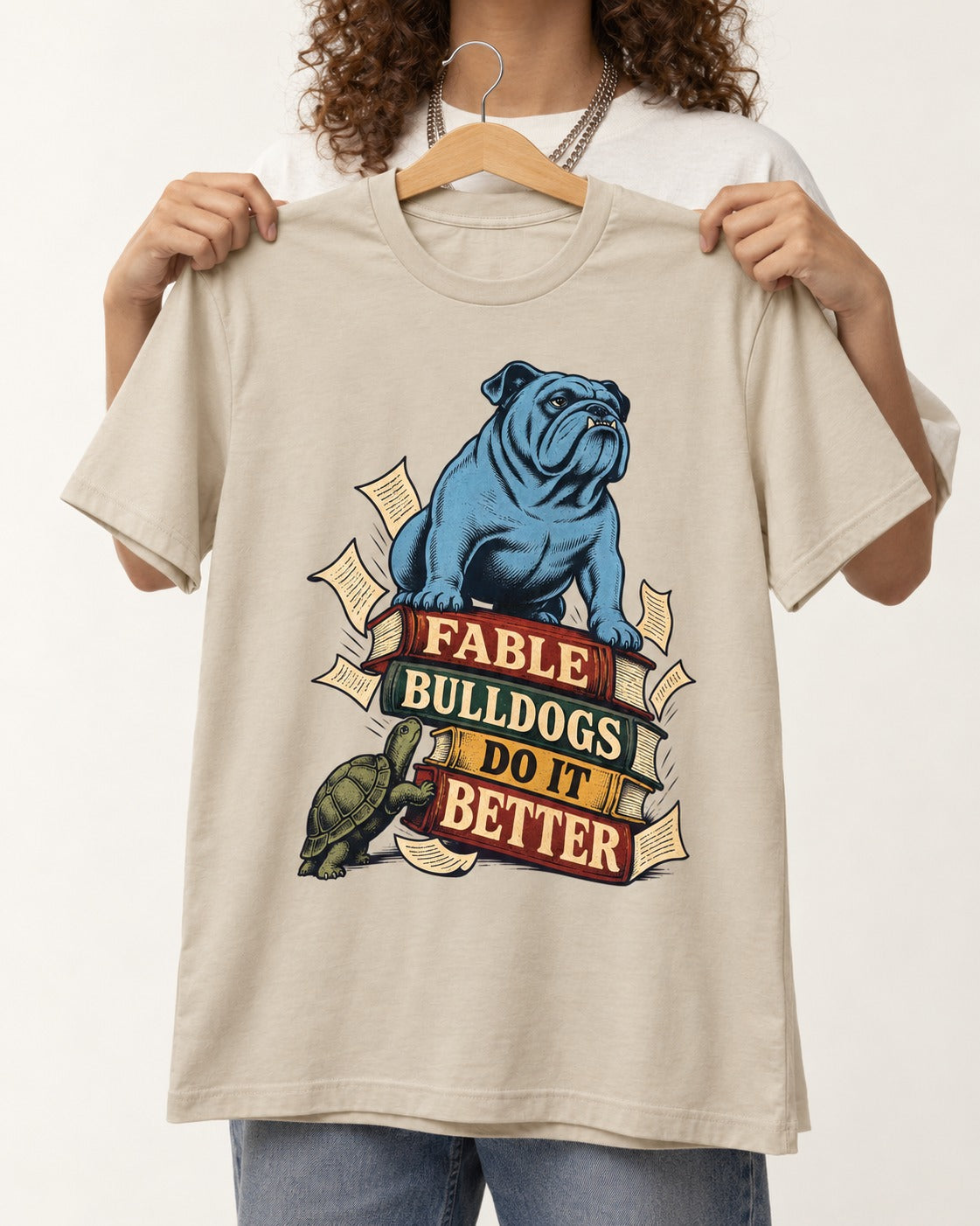 English Bulldog Does It Better T-Shirt in Sand, held up on a hanger