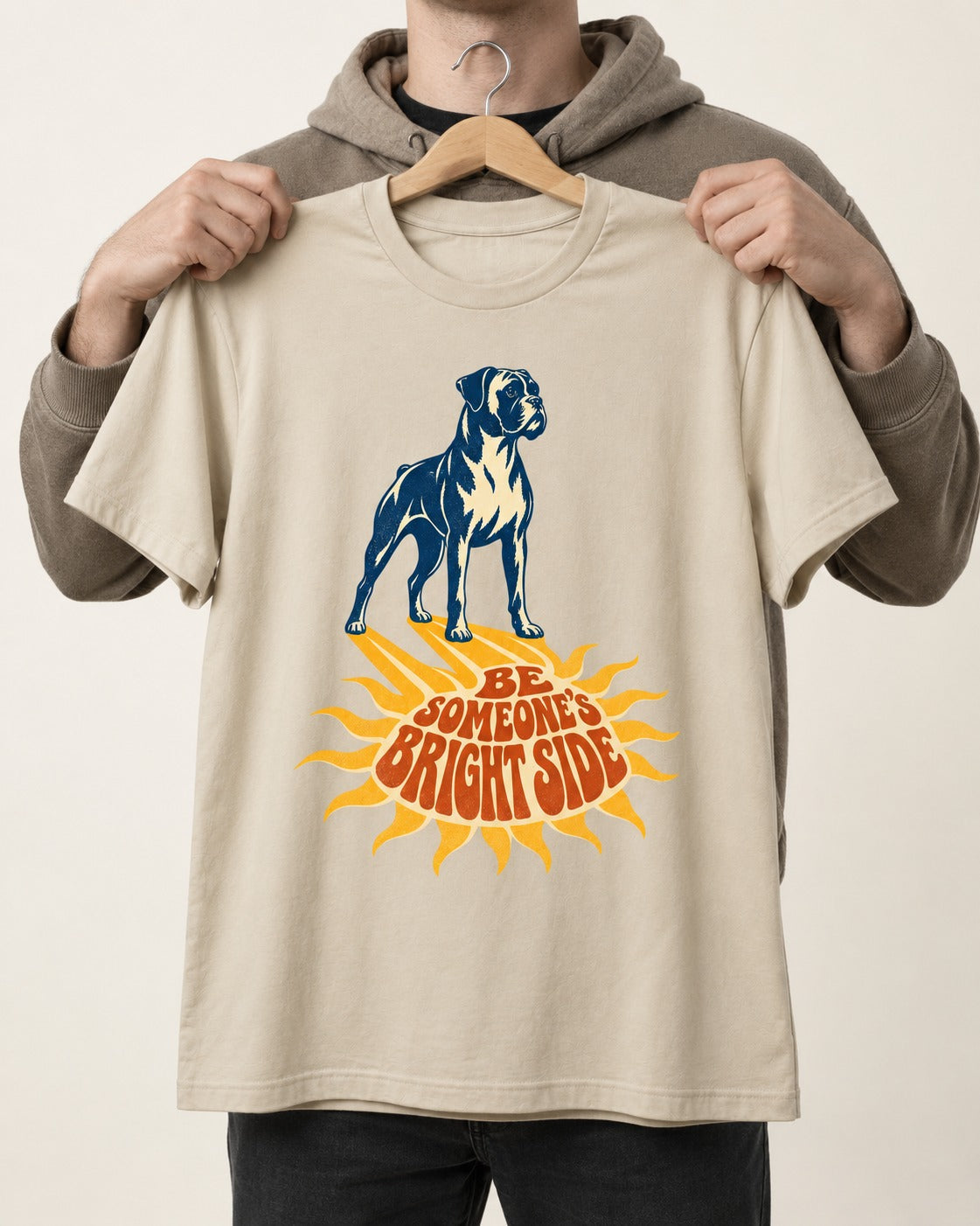 Boxer Be Someone's Bright Side T-Shirt in Sand, held up on a hanger