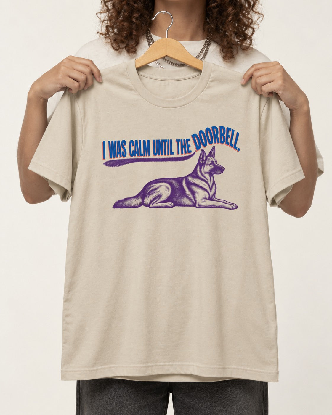 German Shepherd Dog Calm Until the Doorbell T-Shirt in Sand, held up on a hanger