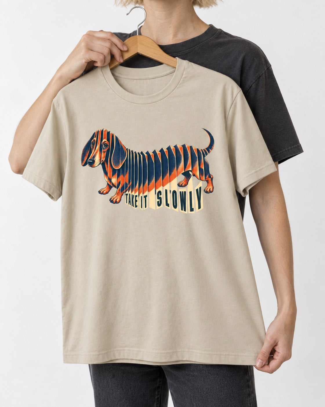 Take It Slowly Dachshund T-Shirt in Sand, held up on a hanger