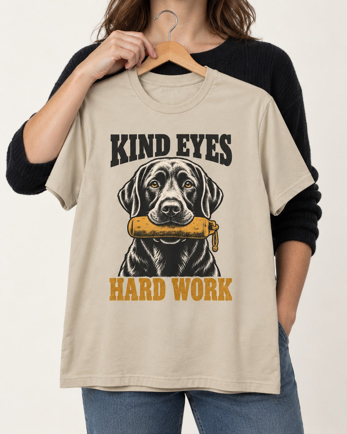 Kind Eyes Hard Work Labrador Retriever T-Shirt in Sand, held up on a hanger