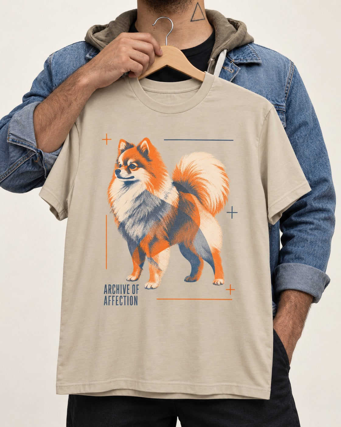Pomeranian Archive of Affection T-Shirt in Sand, held up on a hanger